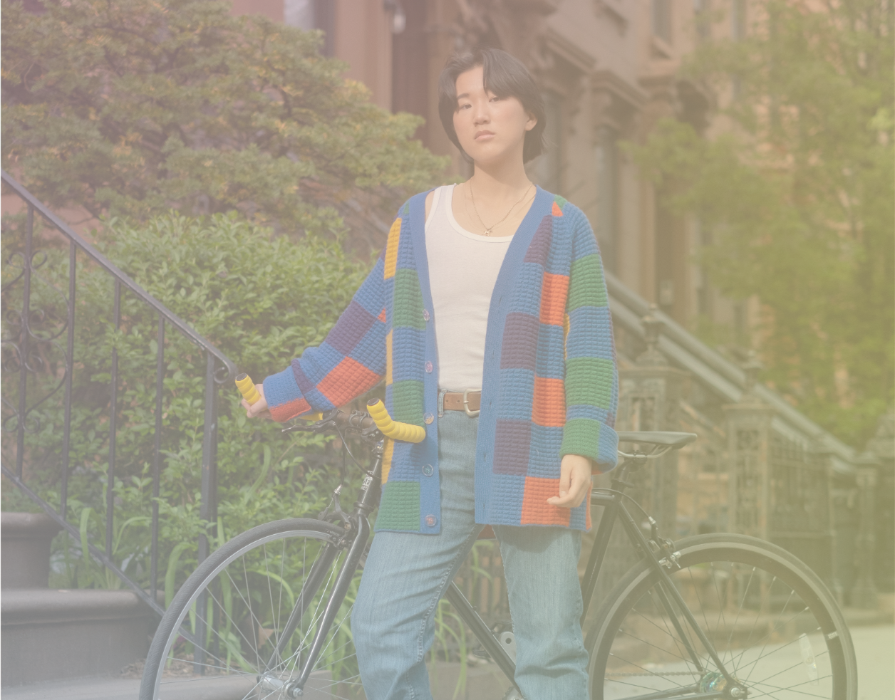 A non-binary trans man standing outside with a bicycle