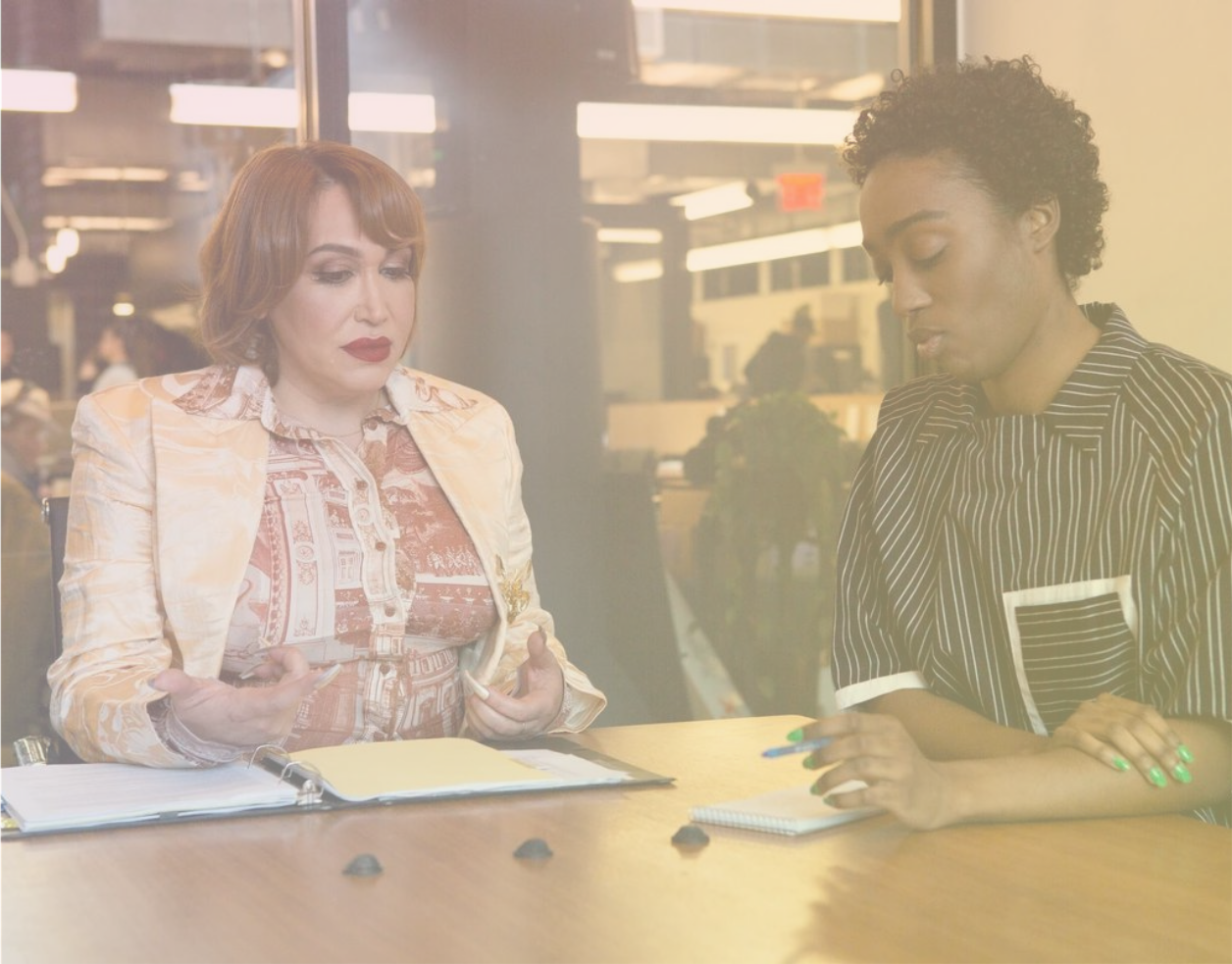 Two gender diverse people sitting at a table at work.